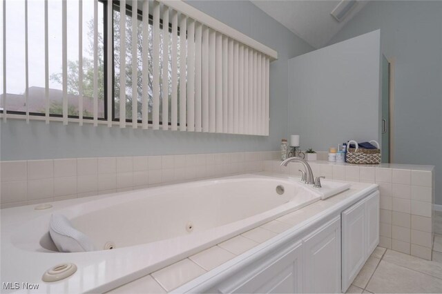 full bath with a tub with jets, tile patterned floors, and lofted ceiling