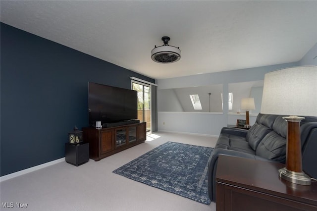 living area featuring a skylight, carpet, and baseboards