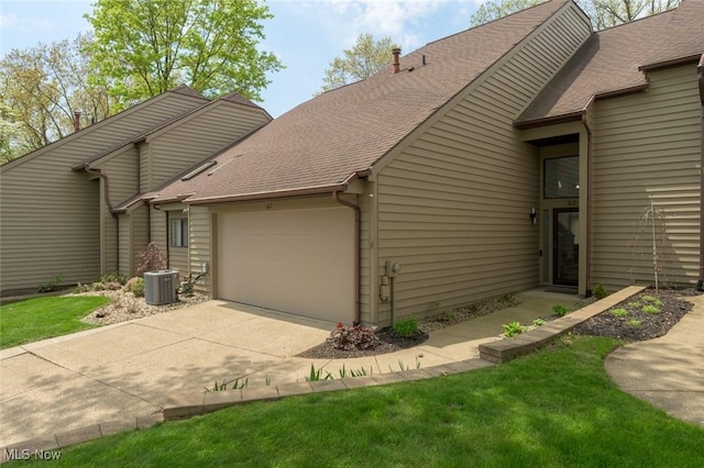view of property exterior with an attached garage, driveway, a shingled roof, and central AC unit