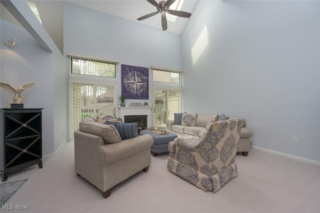 carpeted living room with ceiling fan, high vaulted ceiling, a fireplace, and baseboards