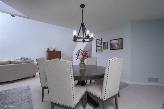 dining space featuring a chandelier, light colored carpet, and baseboards