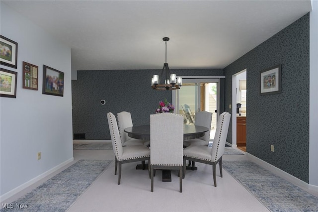 dining space featuring an accent wall, a chandelier, wallpapered walls, and baseboards