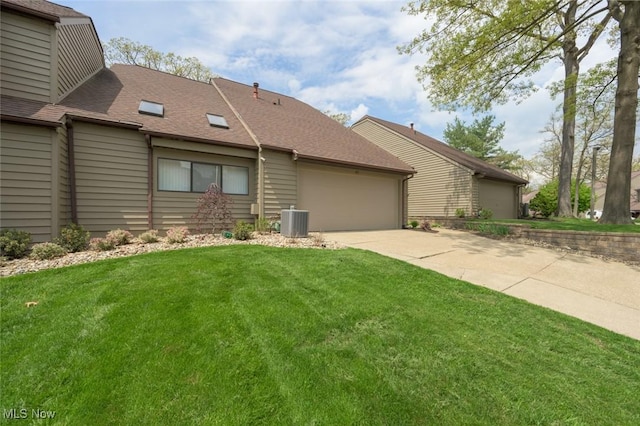 view of front facade with central AC unit, a front yard, a garage, a shingled roof, and driveway