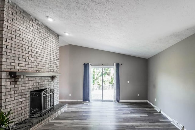 5291 Francesca St NE, Louisville, OH 44641 - unfurnished living room with a textured ceiling, a brick fireplace, wood finished floors, lofted ceiling, and baseboards
