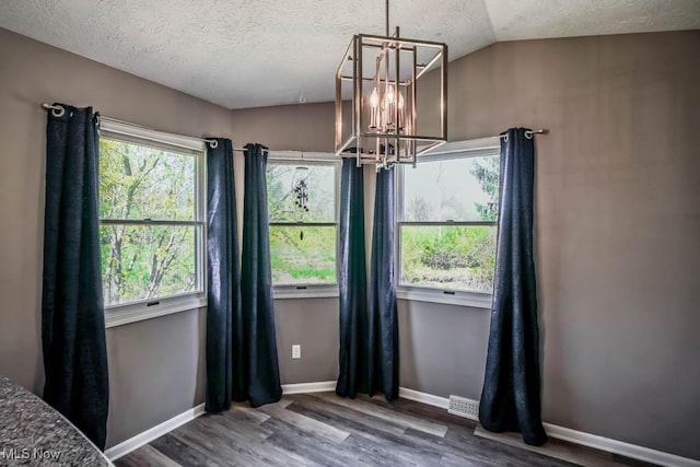 5291 Francesca St NE, Louisville, OH 44641 - unfurnished dining area with a chandelier, wood finished floors, a textured ceiling, baseboards, and lofted ceiling