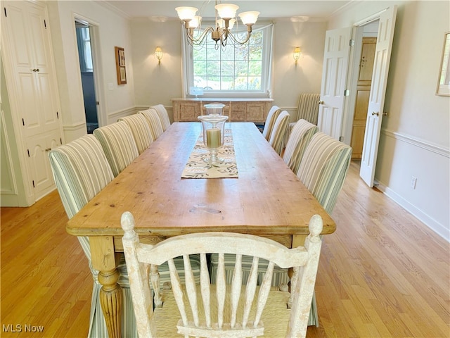 dining area featuring light wood-style floors, crown molding, a chandelier, and baseboards