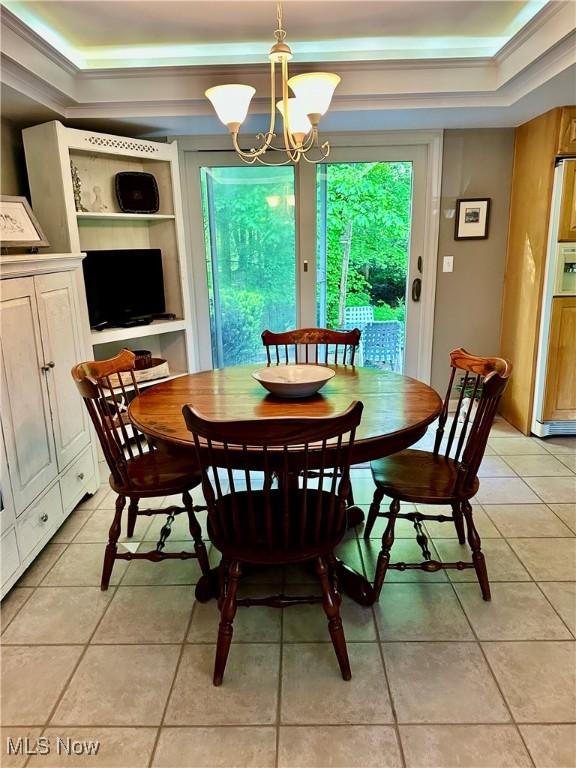 dining space featuring a raised ceiling, a chandelier, and light tile patterned floors