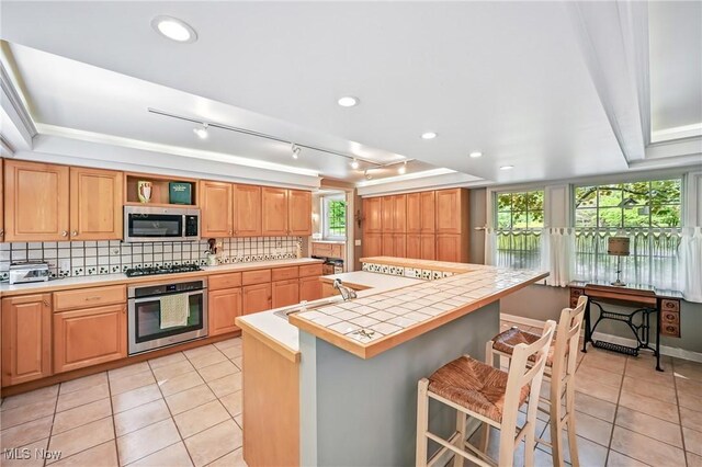 3711 Sampson Rd, Youngstown, OH 44505 - kitchen with appliances with stainless steel finishes, a sink, light tile patterned floors, and a center island with sink