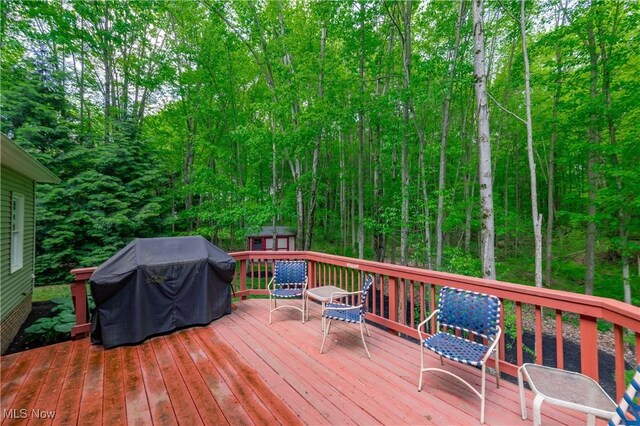 1030 Whisperwood Ln, Aurora, OH 44202 - wooden deck featuring a grill, an outdoor structure, a storage unit, and a forest view
