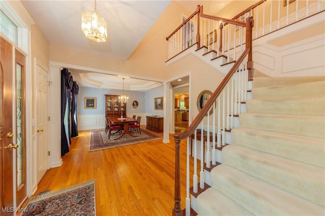 1030 Whisperwood Ln, Aurora, OH 44202 - foyer entrance featuring a chandelier, stairs, light wood-type flooring, a decorative wall, and a wainscoted wall