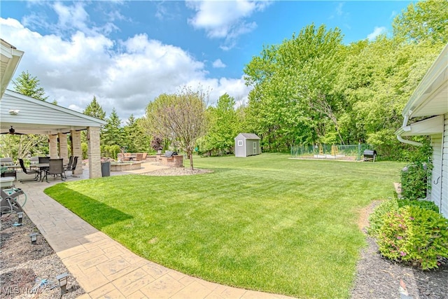 view of grassy yard with a patio area, a storage shed, an outbuilding, and ceiling fan