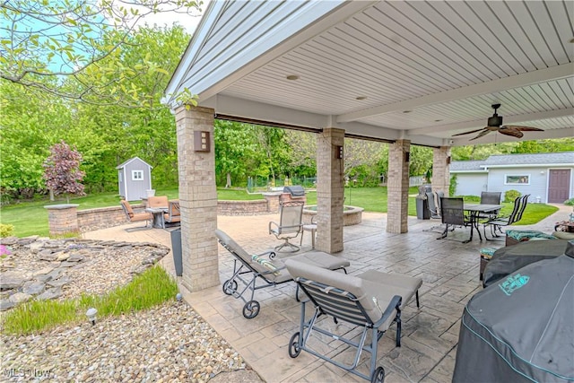 view of patio featuring outdoor dining space, a storage unit, ceiling fan, and an outdoor structure