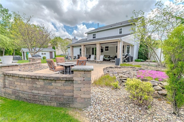 rear view of property with a fire pit, a patio, an outdoor structure, and fence