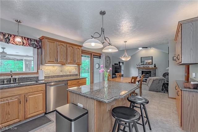 kitchen featuring stainless steel dishwasher, a breakfast bar area, a kitchen island, a textured ceiling, and open floor plan