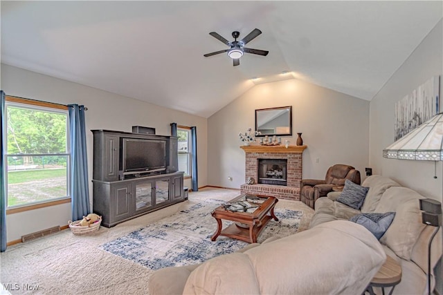 living room featuring vaulted ceiling, ceiling fan, baseboards, light colored carpet, and a brick fireplace