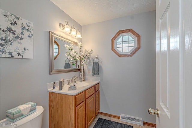 bathroom with plenty of natural light, toilet, vanity, and baseboards