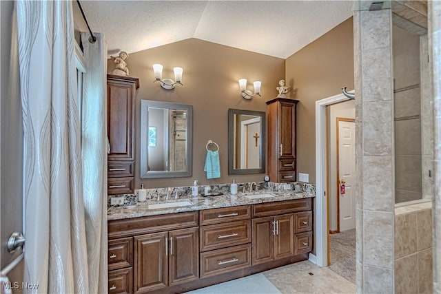 bathroom featuring lofted ceiling, double vanity, tile patterned floors, and a textured ceiling
