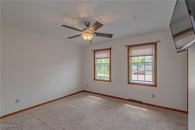 empty room featuring carpet, baseboards, and a ceiling fan