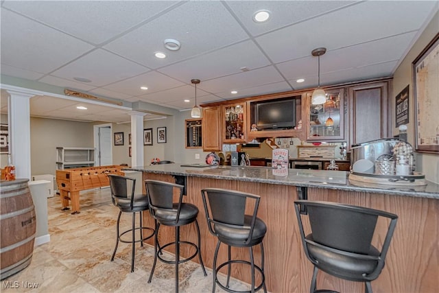 indoor bar with a paneled ceiling, hanging light fixtures, decorative columns, and recessed lighting