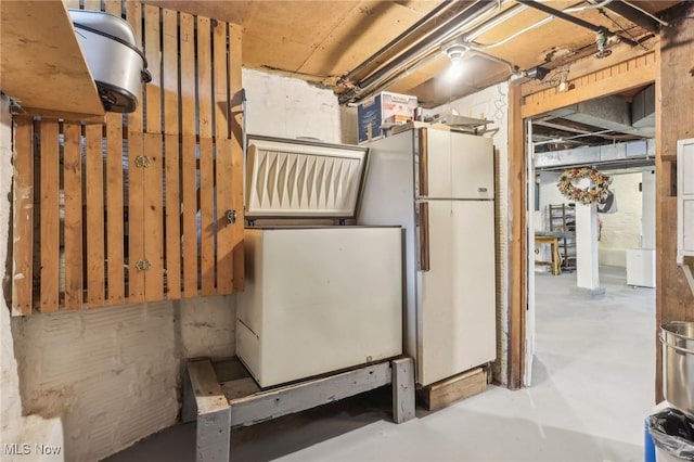 unfinished basement featuring freestanding refrigerator
