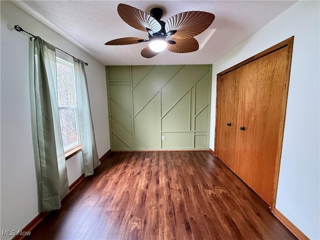 36 Choctaw Trl, Malvern, OH 44644 - unfurnished bedroom with wood finished floors, a closet, baseboards, a textured ceiling, and a decorative wall