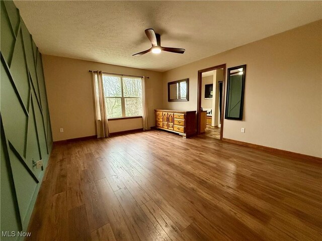 36 Choctaw Trl, Malvern, OH 44644 - unfurnished bedroom with hardwood / wood-style flooring, baseboards, a textured ceiling, and a ceiling fan
