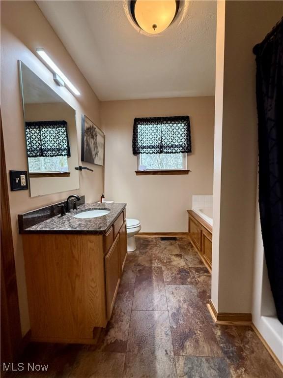 36 Choctaw Trl, Malvern, OH 44644 - full bathroom with baseboards, toilet, stone finish flooring, a bathtub, and vanity