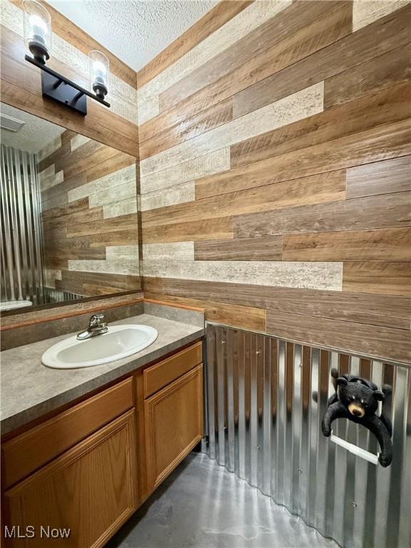 36 Choctaw Trl, Malvern, OH 44644 - bathroom featuring wood walls, finished concrete flooring, a textured ceiling, and vanity