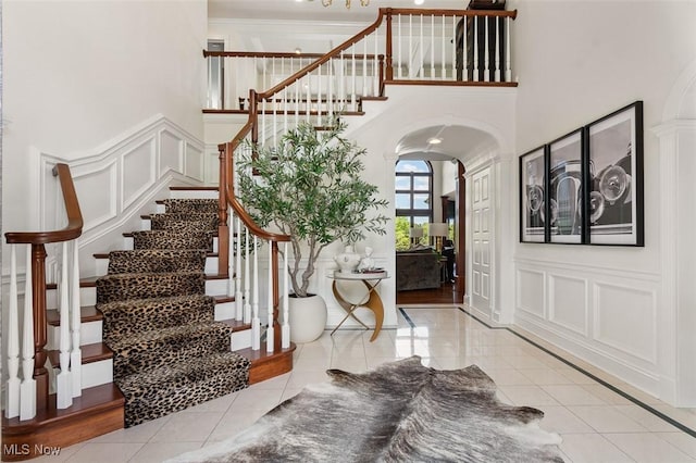 7384 Braucher St NW, North Canton, OH 44720 - entryway featuring arched walkways, a decorative wall, stairs, a high ceiling, and light tile patterned floors