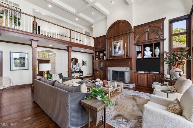 7384 Braucher St NW, North Canton, OH 44720 - living area featuring ornate columns, a high ceiling, beamed ceiling, a premium fireplace, and dark wood-style flooring