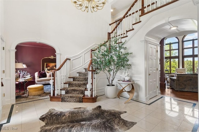 7384 Braucher St NW, North Canton, OH 44720 - tiled entryway featuring arched walkways, decorative columns, a high ceiling, a decorative wall, and stairway