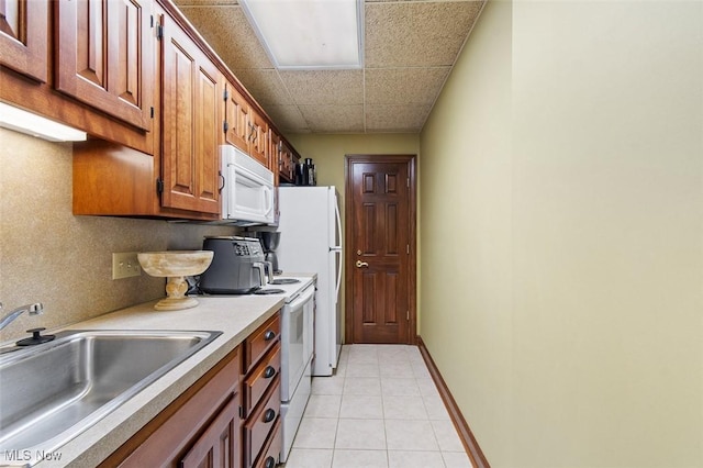 7384 Braucher St NW, North Canton, OH 44720 - kitchen featuring white appliances, a sink, light tile patterned flooring, light countertops, and brown cabinetry