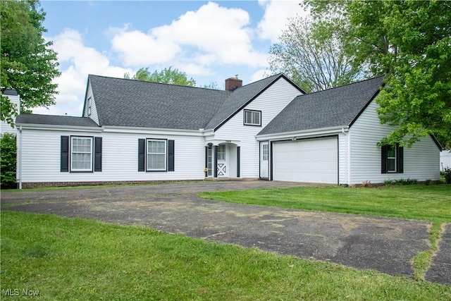7969 Bricker Rd NW, Massillon, OH 44646 - view of front facade featuring a garage, asphalt driveway, a shingled roof, a chimney, and a front lawn