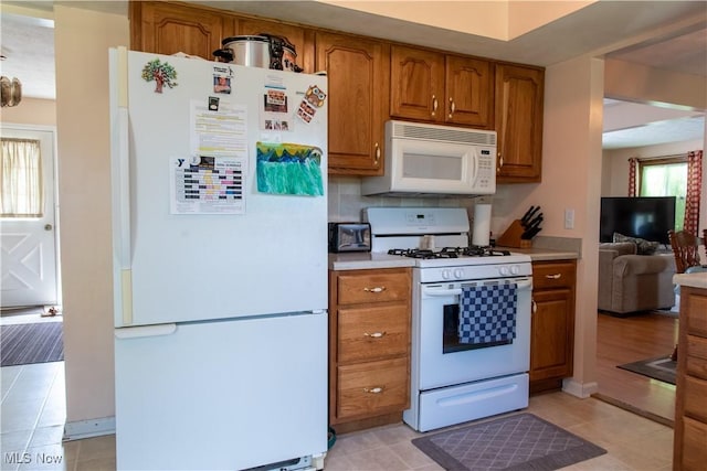 7969 Bricker Rd NW, Massillon, OH 44646 - kitchen featuring white appliances, brown cabinetry, light countertops, light tile patterned flooring, and decorative backsplash