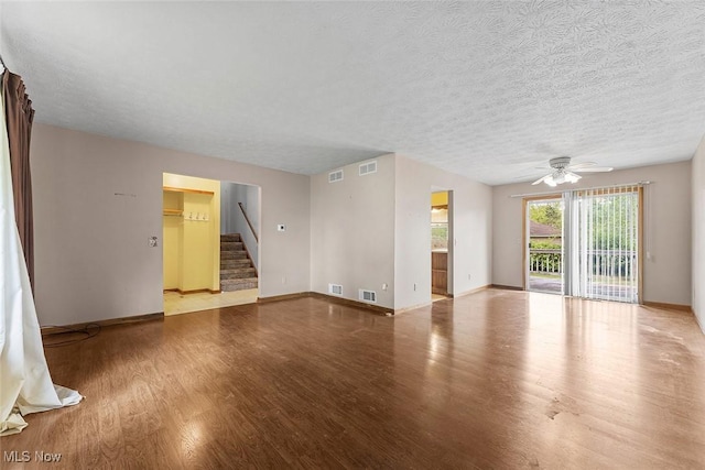 67 Chestnut Ave, Northfield, OH 44067 - unfurnished living room featuring wood finished floors, baseboards, a ceiling fan, stairway, and a textured ceiling