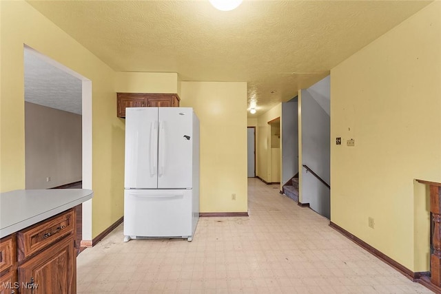 67 Chestnut Ave, Northfield, OH 44067 - kitchen with freestanding refrigerator, light flooring, baseboards, a textured ceiling, and light countertops