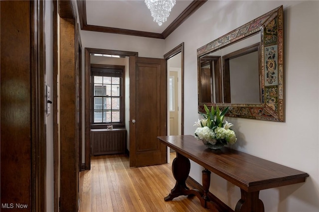 doorway to outside with radiator heating unit, light wood finished floors, crown molding, and a chandelier