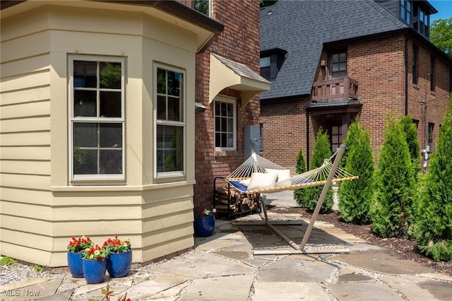 view of property exterior with roof with shingles and brick siding