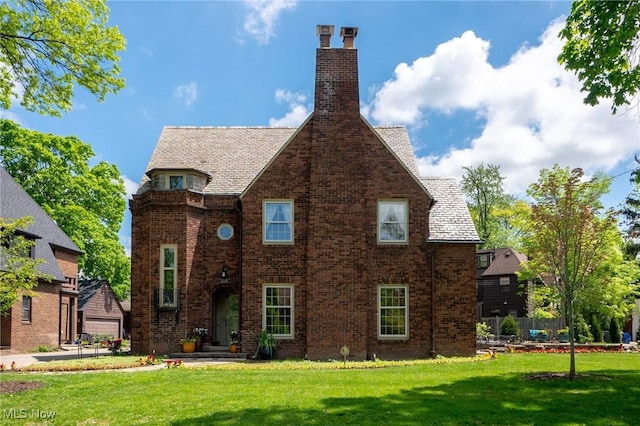 view of front of property featuring a chimney, a front yard, and brick siding