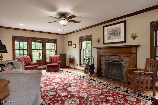living area featuring ceiling fan, wood finished floors, a fireplace, recessed lighting, and ornamental molding