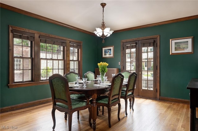 dining space featuring baseboards, french doors, crown molding, light wood-style flooring, and a chandelier