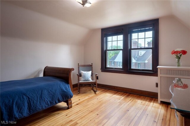 bedroom with lofted ceiling, light wood-style flooring, and baseboards