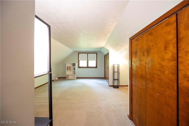 8665 Prescott Dr, Chesterland, OH 44026 - additional living space with a textured ceiling, vaulted ceiling, light colored carpet, and baseboards
