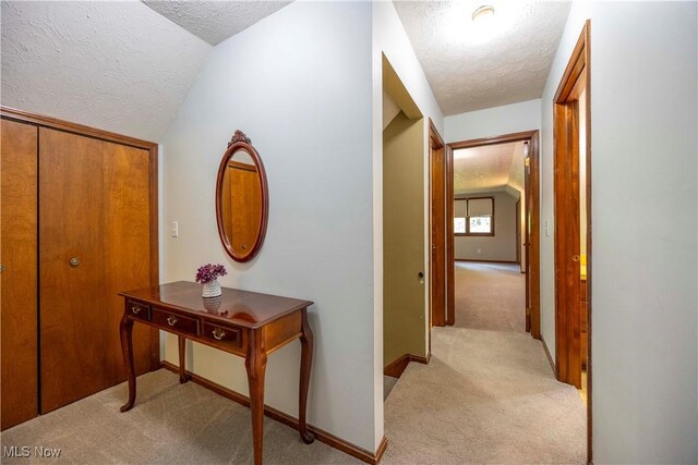 8665 Prescott Dr, Chesterland, OH 44026 - hall with a textured ceiling, light carpet, vaulted ceiling, and baseboards