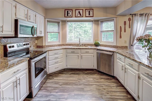 650 Thornhill Ln, Aurora, OH 44202 - kitchen featuring appliances with stainless steel finishes, wood finished floors, white cabinets, and light stone counters