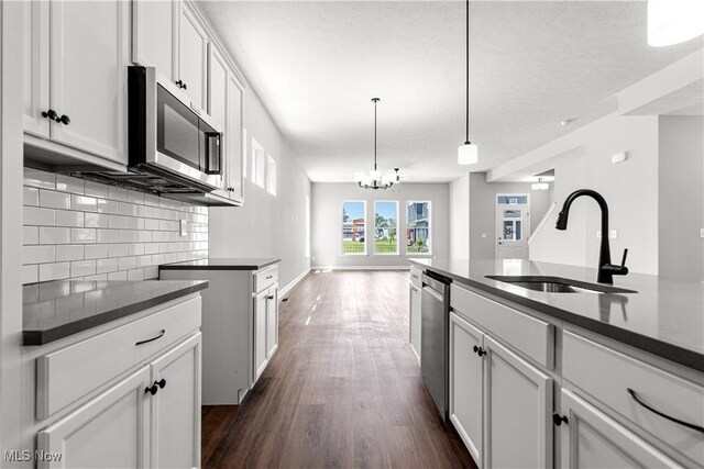 374 Bascule Dr, Lorain, OH 44052 - kitchen with appliances with stainless steel finishes, tasteful backsplash, a chandelier, dark wood-type flooring, and dark countertops