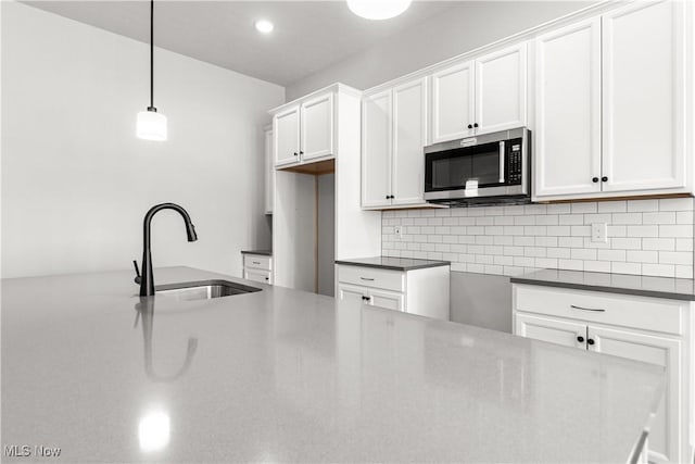 374 Bascule Dr, Lorain, OH 44052 - kitchen with stainless steel microwave, tasteful backsplash, white cabinetry, pendant lighting, and recessed lighting