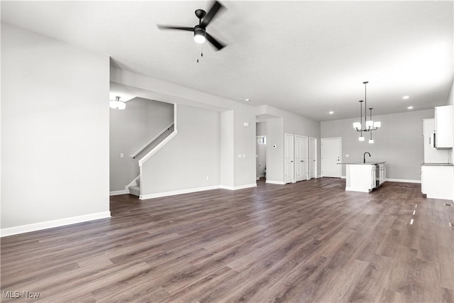 374 Bascule Dr, Lorain, OH 44052 - unfurnished living room featuring dark wood-style flooring, ceiling fan, stairs, recessed lighting, and a chandelier
