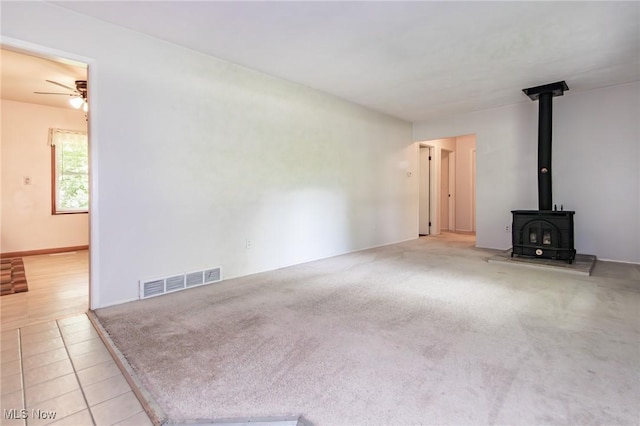 13970 E Willard Rd, Novelty, OH 44072 - unfurnished living room with ceiling fan, a wood stove, and tile patterned floors