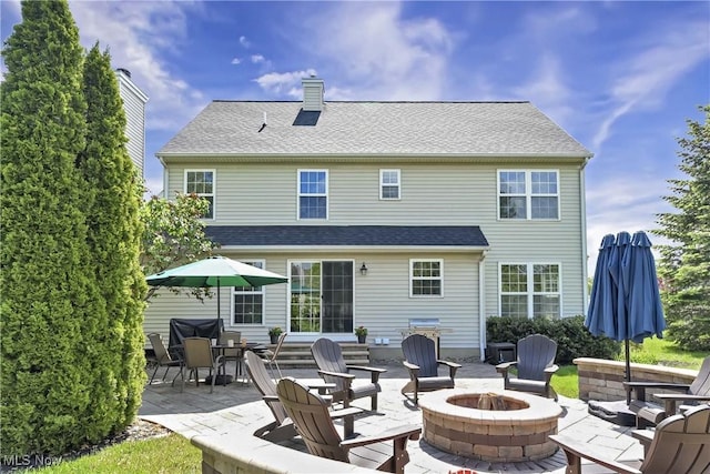 rear view of property featuring an outdoor fire pit, a patio area, and a chimney